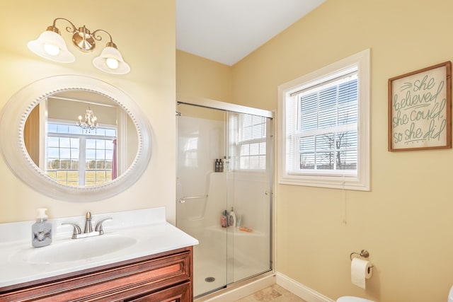 bathroom with toilet, vanity, baseboards, a stall shower, and an inviting chandelier