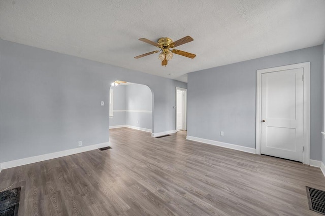 spare room with visible vents, arched walkways, ceiling fan, and baseboards