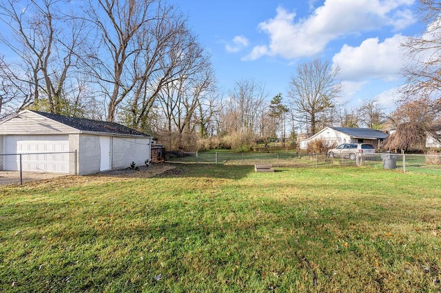 view of yard featuring a garage, an outbuilding, and fence