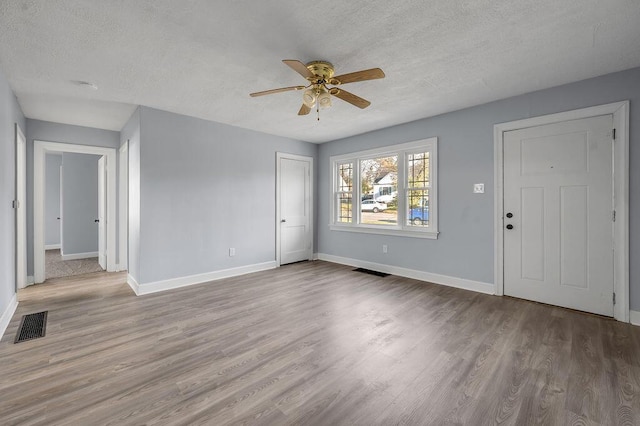 entrance foyer featuring light wood finished floors, baseboards, visible vents, and a textured ceiling