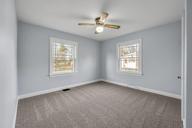 carpeted empty room featuring visible vents, plenty of natural light, baseboards, and ceiling fan