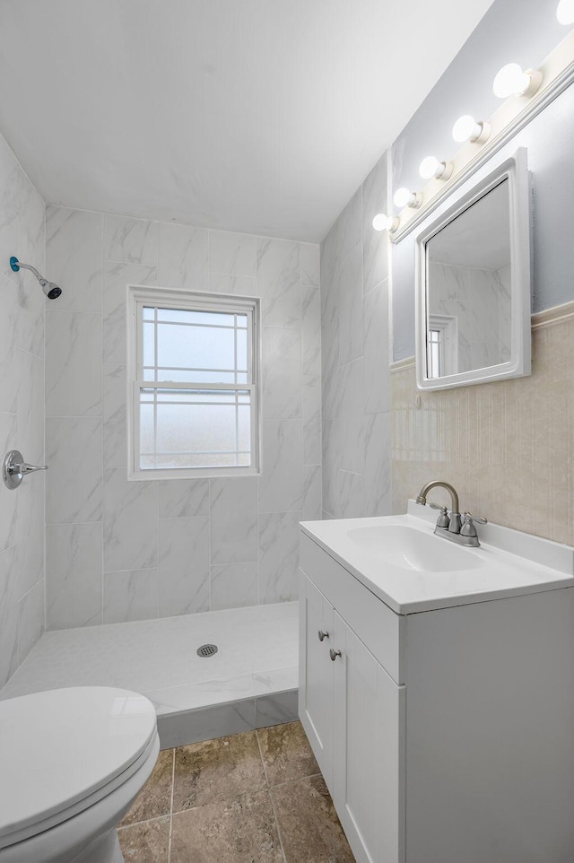 full bathroom featuring a stall shower, vanity, toilet, and tile walls