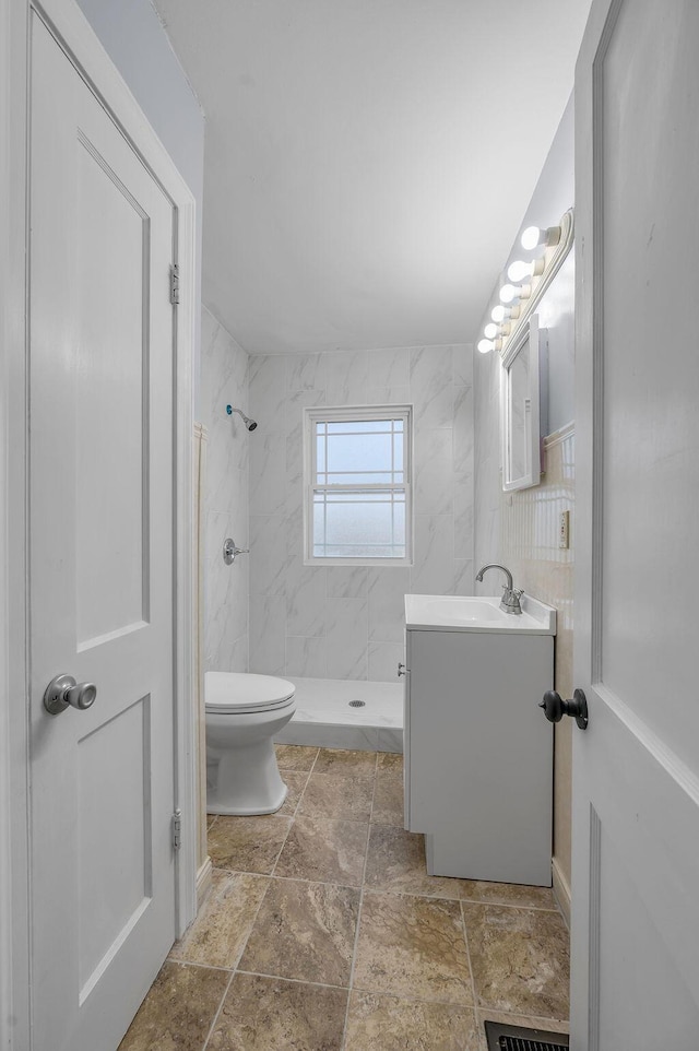 full bathroom featuring toilet, a stall shower, vanity, and tile walls