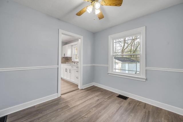 empty room with baseboards, visible vents, and wood finished floors