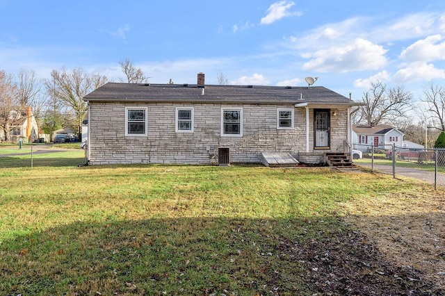 rear view of house featuring stone siding, a fenced backyard, a chimney, and a yard