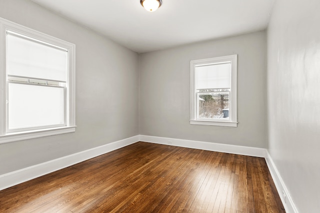 spare room with baseboards and wood finished floors