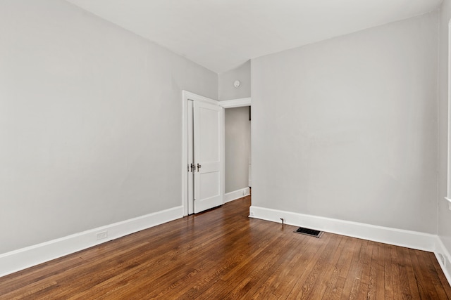 spare room with visible vents, baseboards, and dark wood finished floors