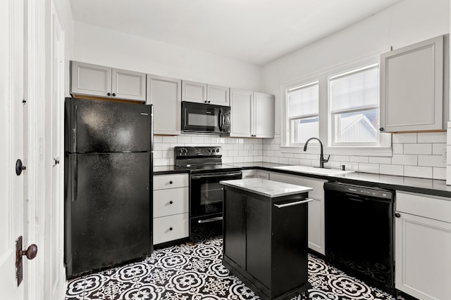 kitchen featuring decorative backsplash, dark countertops, a kitchen island, black appliances, and a sink