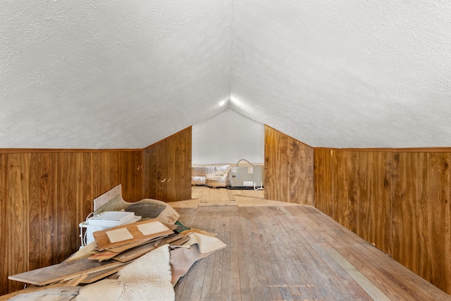 bonus room with wooden walls and a textured ceiling