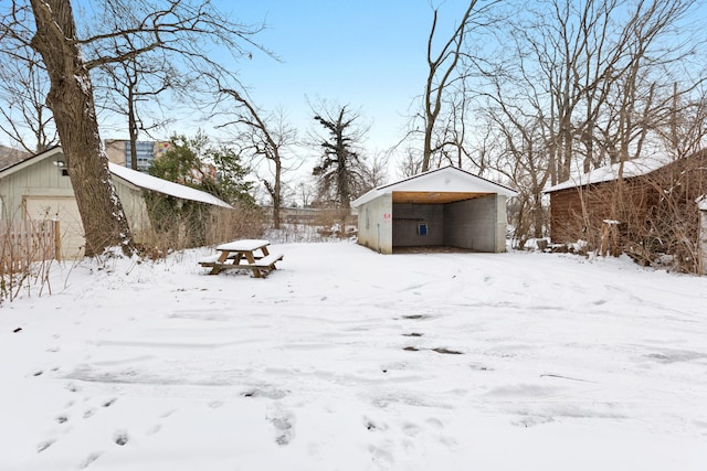 snowy yard with a garage and a carport