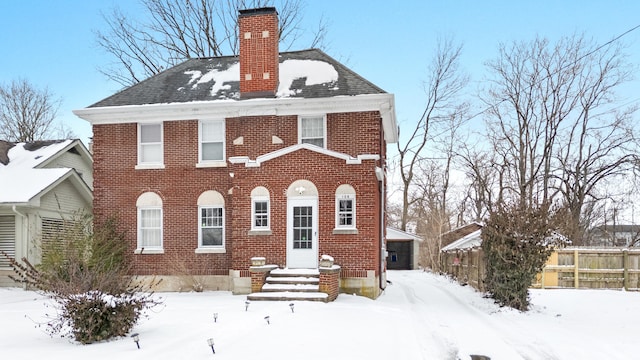 view of front of property with a chimney, fence, and brick siding