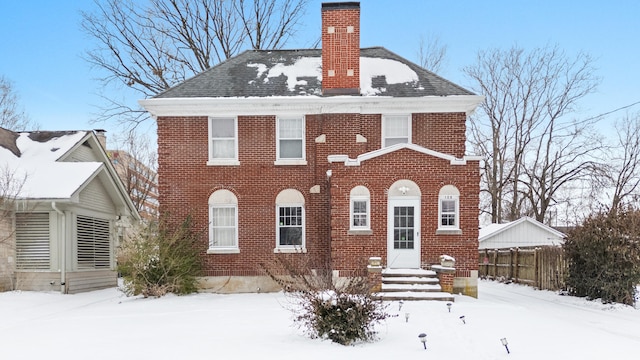 view of front of property featuring a shingled roof, brick siding, and a chimney