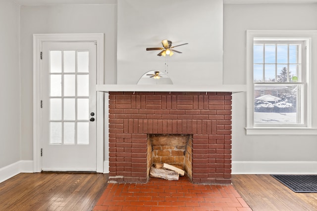 unfurnished living room with visible vents, a fireplace, baseboards, and wood finished floors