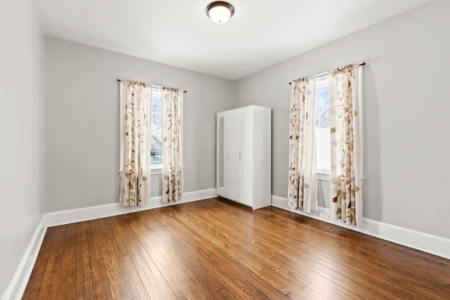 spare room with plenty of natural light, baseboards, and wood finished floors