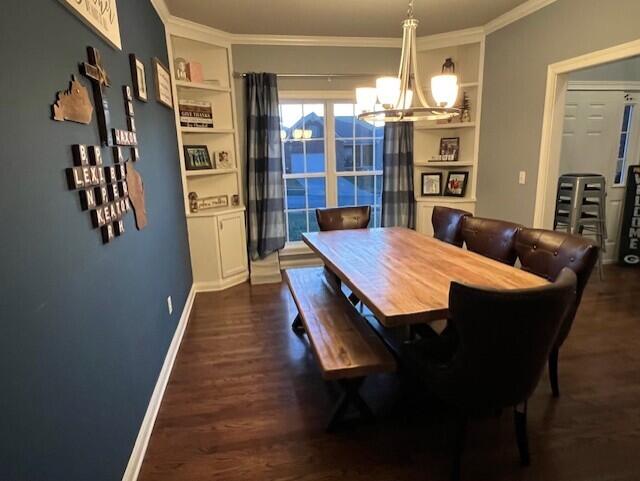 dining room with a notable chandelier, baseboards, built in features, dark wood-style floors, and crown molding