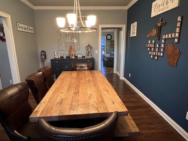 dining area with dark wood-style floors, crown molding, baseboards, and a notable chandelier