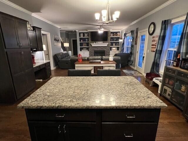 kitchen featuring crown molding, a center island, dark wood-style flooring, and a fireplace