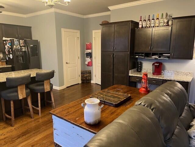 living room with dark wood-style floors, ornamental molding, a chandelier, and baseboards