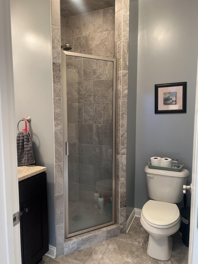 full bathroom featuring baseboards, a shower stall, toilet, and vanity