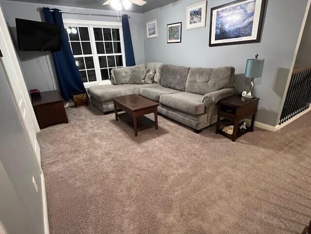 carpeted living area featuring a ceiling fan and baseboards