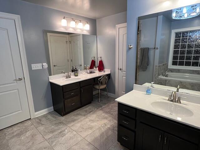 bathroom featuring a garden tub, vanity, and baseboards