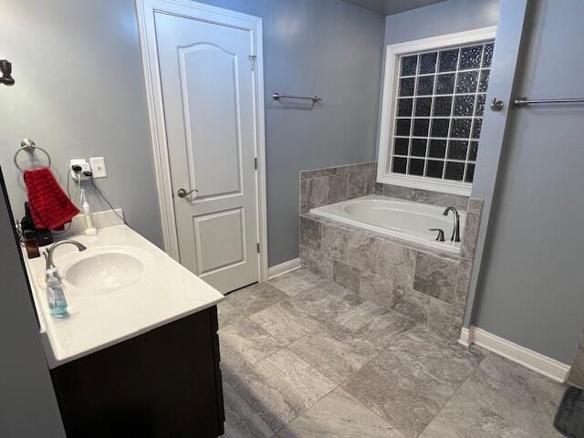 full bath with vanity, baseboards, and a bath