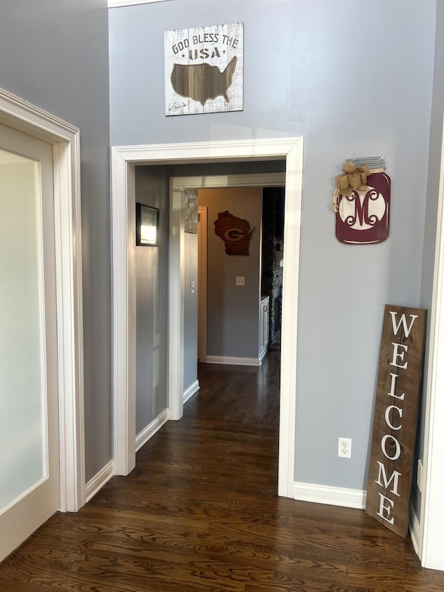 hallway featuring baseboards and dark wood-type flooring