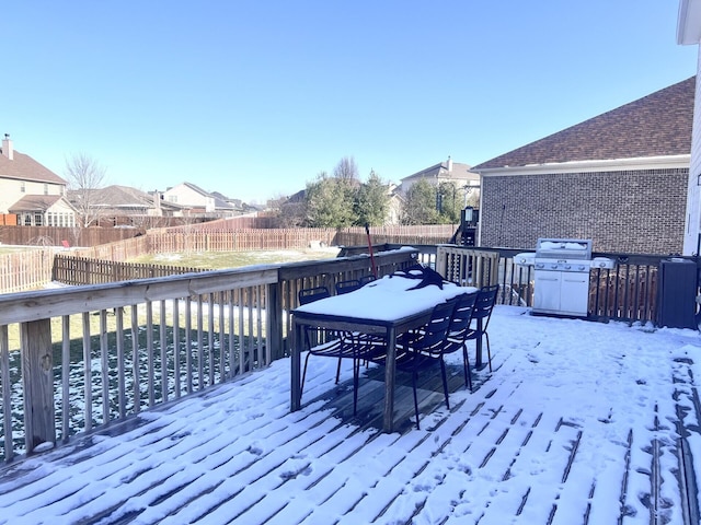 snow covered deck with outdoor dining area, a fenced backyard, a residential view, and a grill