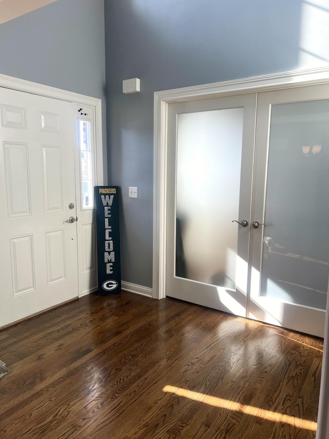 entryway with dark wood-style floors, lofted ceiling, and baseboards