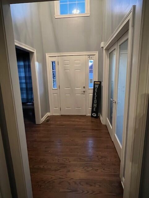 foyer featuring dark wood-style floors, a high ceiling, and baseboards