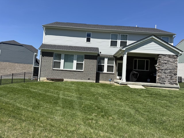 rear view of property featuring a shingled roof, a yard, a patio area, fence, and brick siding