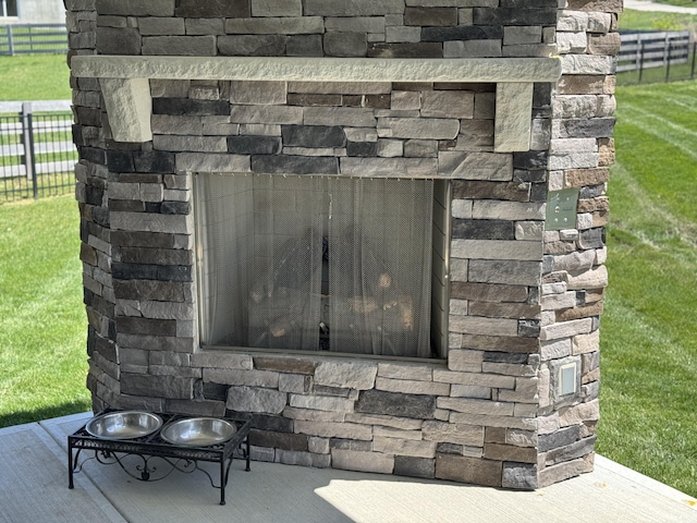 details featuring fence and an outdoor stone fireplace
