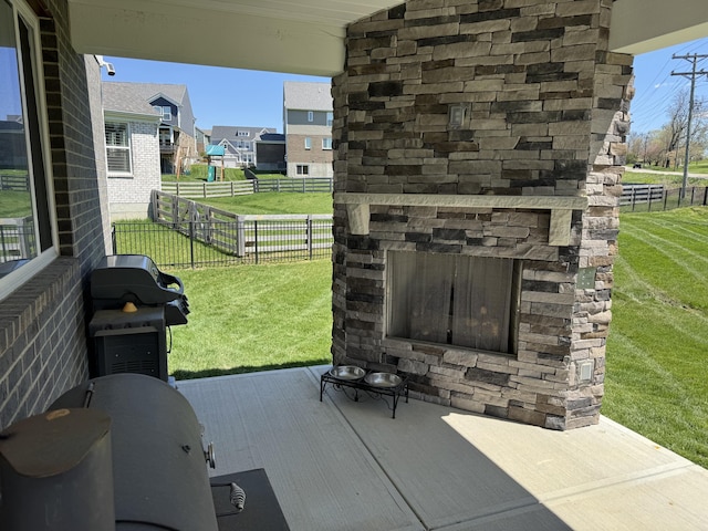 view of patio featuring grilling area, a fenced backyard, an outdoor stone fireplace, and a residential view