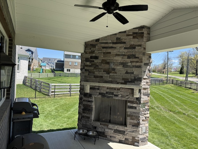 exterior details featuring a fenced backyard, ceiling fan, and an outdoor stone fireplace