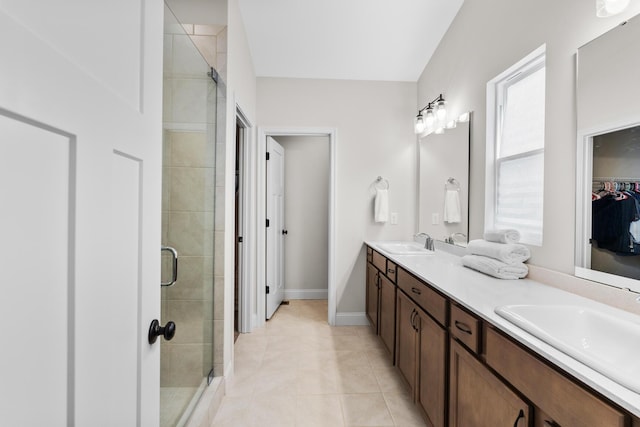 full bath with a stall shower, double vanity, a sink, and a spacious closet