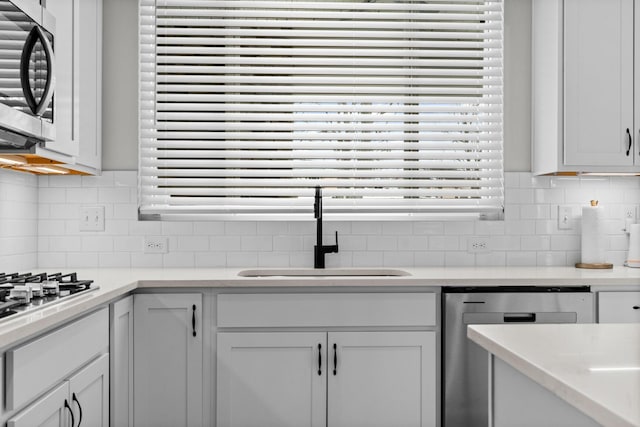 kitchen with a sink, light countertops, decorative backsplash, and stainless steel appliances