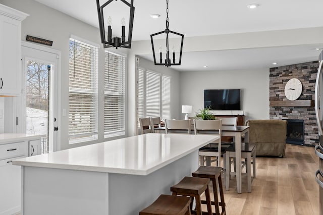kitchen with light countertops, light wood finished floors, a chandelier, and a healthy amount of sunlight