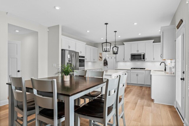 kitchen featuring a sink, stainless steel appliances, a kitchen island, and white cabinetry