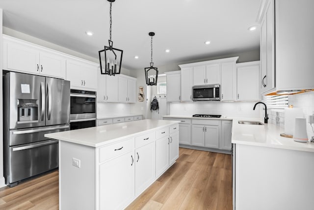 kitchen featuring recessed lighting, light countertops, a center island, stainless steel appliances, and a sink
