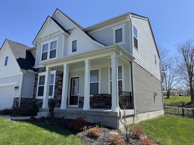 view of front facade with a front lawn, a porch, brick siding, a garage, and fence