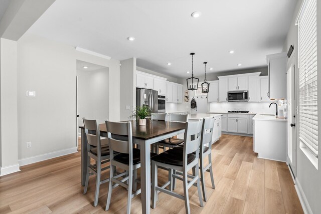 kitchen with white cabinetry, appliances with stainless steel finishes, light countertops, and decorative light fixtures