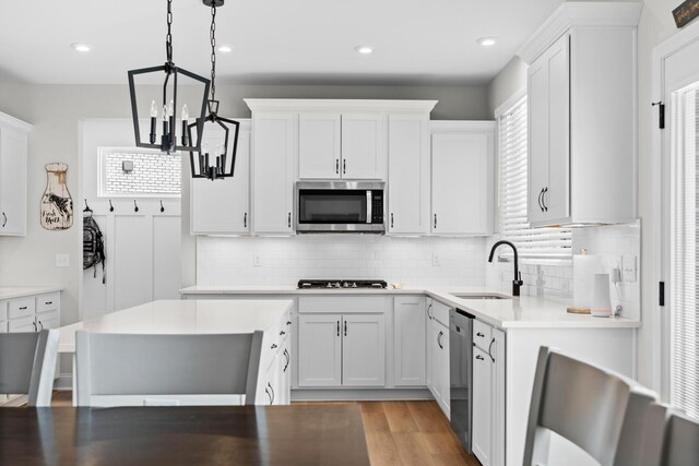 kitchen featuring a center island, stainless steel appliances, light countertops, hanging light fixtures, and white cabinets