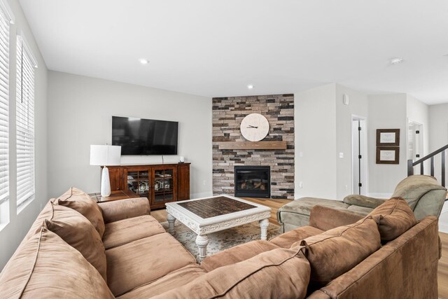 living room featuring light wood finished floors, a stone fireplace, recessed lighting, and baseboards