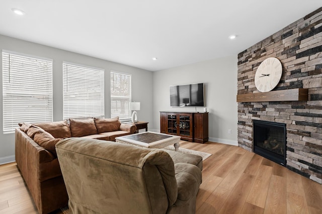 living room with recessed lighting, a stone fireplace, light wood finished floors, and baseboards