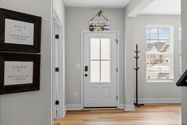 doorway featuring light wood-style flooring and baseboards