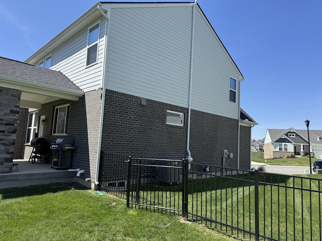 view of side of home with a yard, fence, and brick siding
