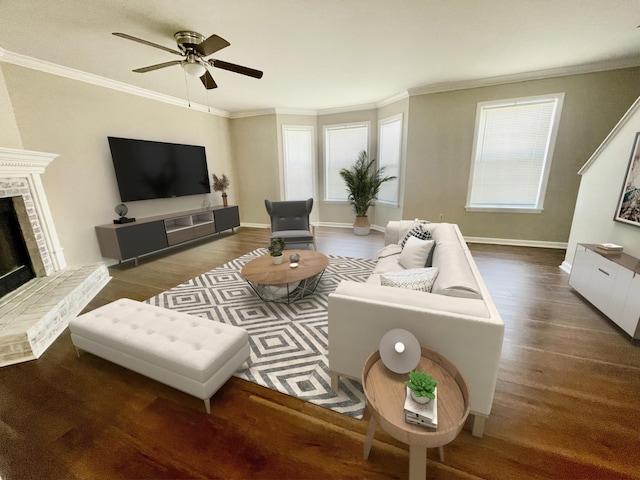 living area featuring ornamental molding, a brick fireplace, ceiling fan, wood finished floors, and baseboards