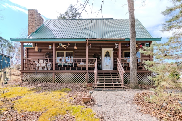 view of front of house with metal roof, a chimney, log exterior, and a ceiling fan