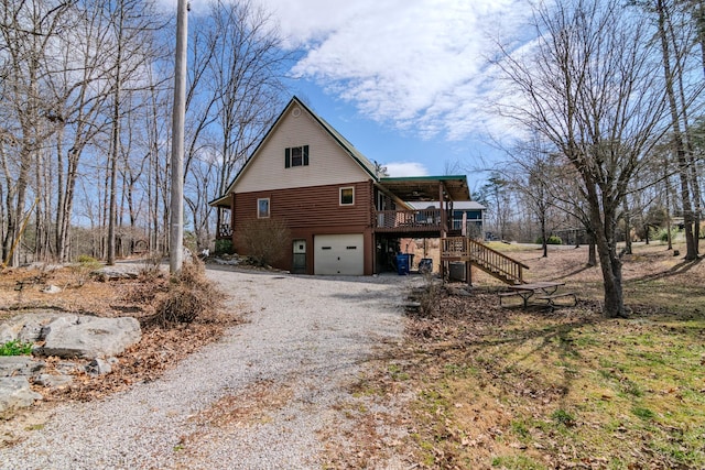 view of side of home with driveway, a garage, and stairway