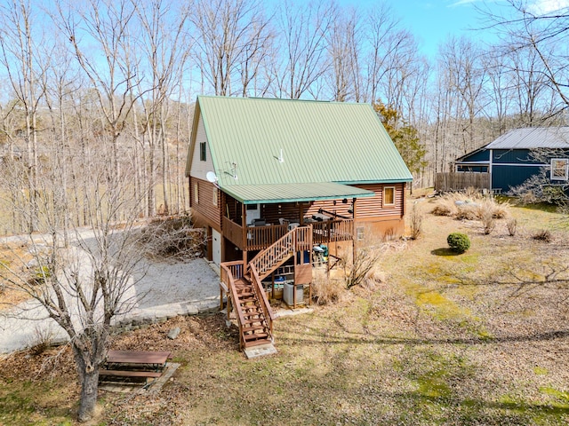 view of property exterior with driveway, log exterior, metal roof, an attached garage, and stairs